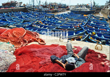 Fisherman sleeping on nets at the port in Essaouira, Morocco Stock Photo