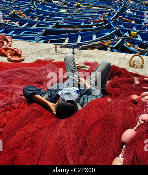 Fisherman sleeping on nets in the harbour in Essaouira, Morocco Stock Photo