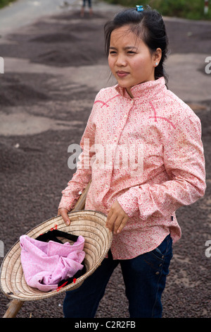 Worker among drying coffee beans on the road in the Vietnam highlands Stock Photo