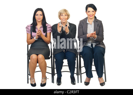 Three business women sitting on chairs in a row and clapping their hands isolated on white background Stock Photo