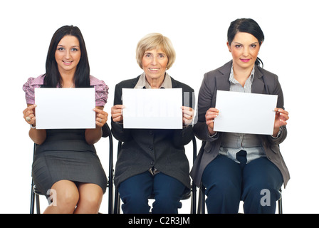 Group of three business women sitting on chairs in a line showing blank pages isolated on white background Stock Photo