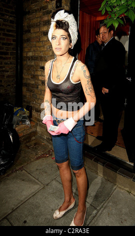 Amy Winehouse, wearing pink gloves, did some spring cleaning at her house. She takes a break and asks photographers for money Stock Photo