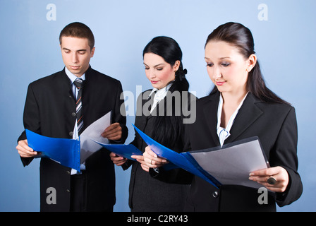 Business team people holding blue folders with contracts and reading in front of blue background Stock Photo