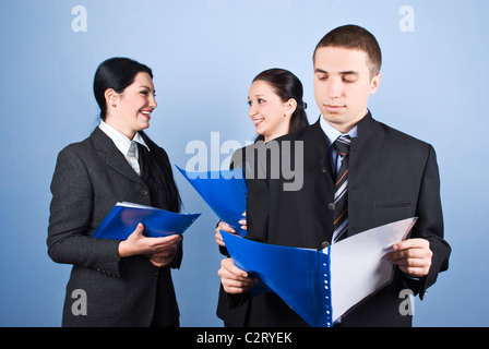 Business man being serious standing in front of camera reading a contract and his colleagues women holding contracts  paperwork Stock Photo