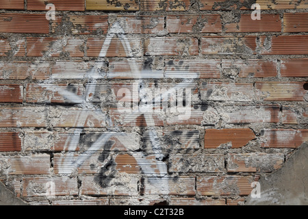 one white star graffiti design drawing on old dirty brick wall in sun Stock Photo