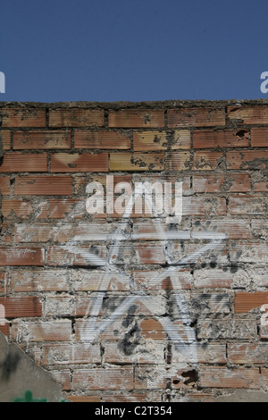 one white star graffiti design drawing on old dirty brick wall in sun Stock Photo