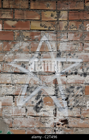 one white star graffiti design drawing on old dirty brick wall in sun Stock Photo