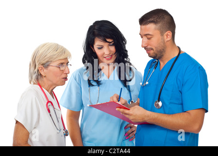 Three diverse doctors having a discussion ,writing and reading on clipboard and smiling satisfied about results isolated Stock Photo