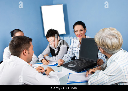 Business people around a table using a laptop and having an conversation at meeting Stock Photo