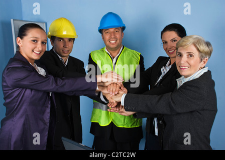 United team of happy architects or engineers with their hands together on blue background Stock Photo