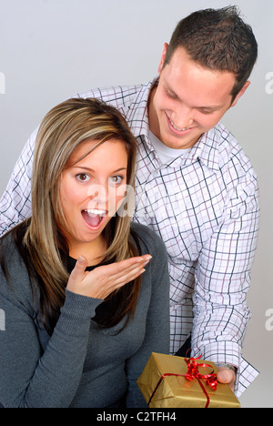 Young Man Giving His Girlfriend A Surprise Birthday Gift Stock Photo