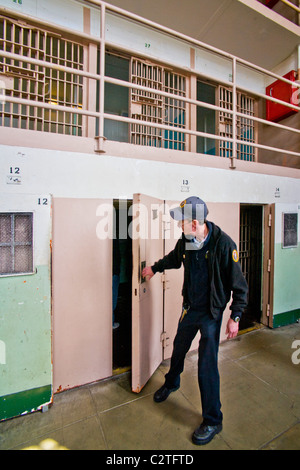 A uniformed volunteer opens the door of a solitary confinement cell to tourists in Cellblock D at the former Alcatraz Prison. Stock Photo