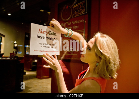 A speed dating hostess posts a sign on the door of a California restaurant. In speed dating, men and women are rotated to meet Stock Photo