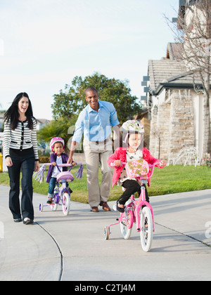 Parents watching children ride bicycles Stock Photo