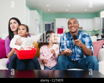 Family sitting on sofa watching television Stock Photo