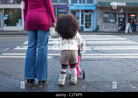 Mixed race mother and daughter crossing street Stock Photo