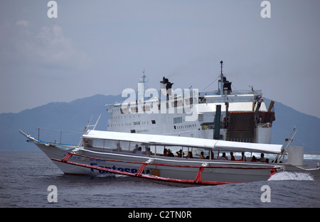 Philippine Super Ferry transports passengers across the seas off Puerto Galera, Mindoro, Philippines as does a smaller banca. Stock Photo