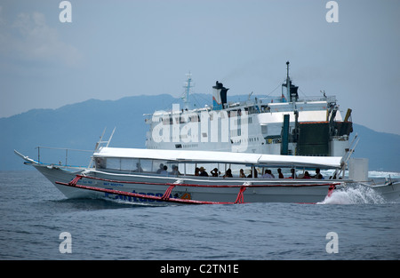 Philippine Super Ferry transports passengers across the seas off Puerto Galera, Mindoro, Philippines as does a smaller banca. Stock Photo