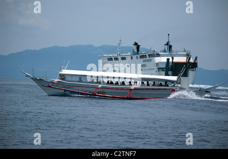 Philippine Super Ferry transports passengers across the seas off Puerto Galera, Mindoro, Philippines as does a smaller banca. Stock Photo