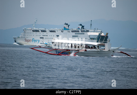 Philippine Super Ferry transports passengers across the seas off Puerto Galera, Mindoro, Philippines as does a smaller banca. Stock Photo