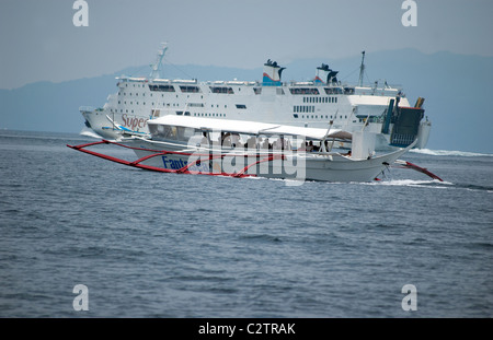 Philippine Super Ferry transports passengers across the seas off Puerto Galera, Mindoro, Philippines as does a smaller banca. Stock Photo