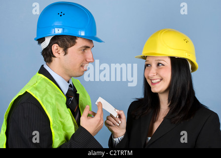 Two young architects having a meeting and both flirting ,the woman giving him a visiting card to calling her Stock Photo