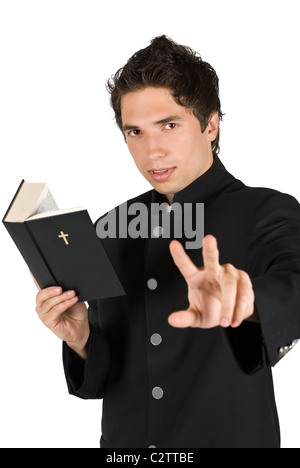 Young priest reading from bible and talking with you gesturing same time to listen him or showing peace sign,focus on his face Stock Photo