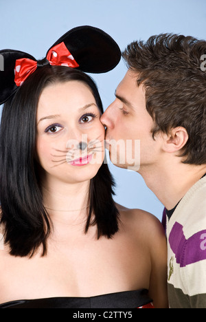 Portrait of a young man in profile kissing a woman with mouse ears on her cheek Stock Photo