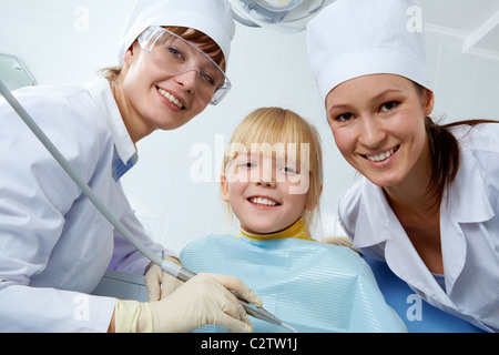 Group of dentist, assistant and little girl looking at camera Stock Photo