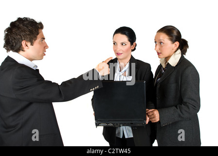 Mad boss screaming at his employees while the two woman holding and using a laptop and looking very surprised and shocked at him Stock Photo