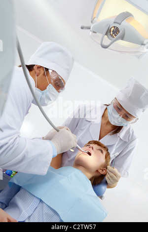 Image of woman opening her mouth and doctor and nurse healing her teeth Stock Photo