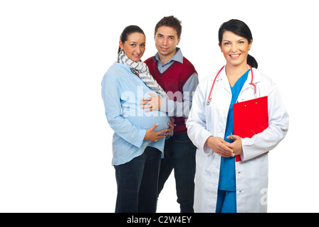 Friendly doctor with clipboard in front of image smiling and a pregnant woman with her husband standing in background Stock Photo