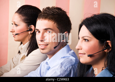 Portrait of operators working in a call center,the man in middle of two woman facing you Stock Photo