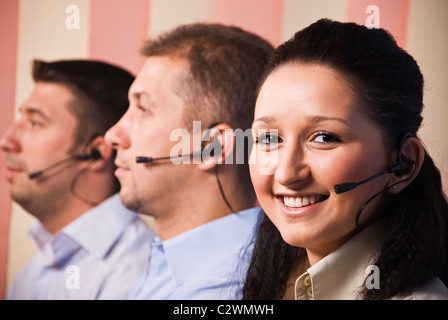 Three people sales representative working in office,focus on woman smiling,men standing in profile with headset Stock Photo