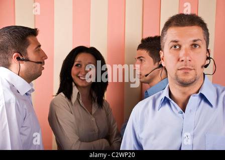 Teamwork customer service with a mid adult man in front and others that having a conversation in background Stock Photo