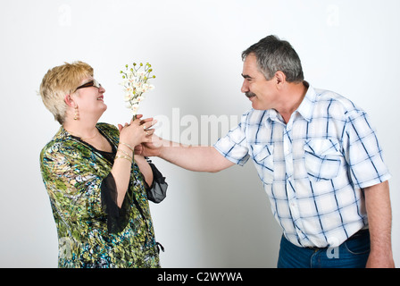 Middle aged man giving flowers to his wife and the woman looking surprised Stock Photo