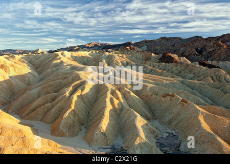 Evening light warms the colorful badlands of Golden Canyon in California's Death Valley National Park. Stock Photo