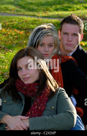 Three Friends Sitting On A Hillside Outside On A Sunny The Fall Autumn Day Stock Photo