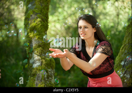 Caucasian woman trying to catch bubbles in her hands Stock Photo