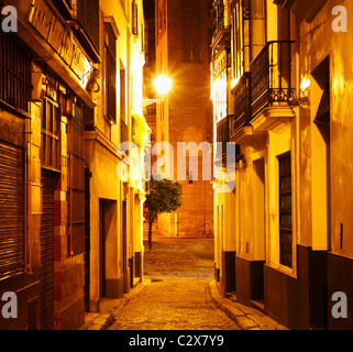 Narrow street in barrio Santa Cruz with Giralda tower in distance. Seville, Andalusia, Spain Stock Photo