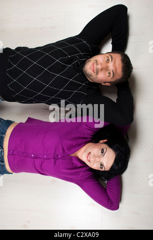 Top view of happy couple lying down on white wooden floor in their new home Stock Photo