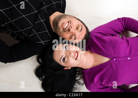 Top view of happy young couple lying down on wooden floor Stock Photo