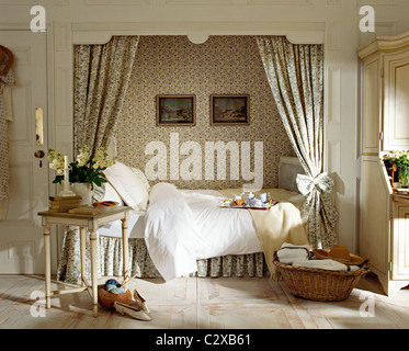 Double bed set in recess with patterned curtains and wallpaper Stock Photo