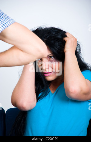 Scared abused woman with bruises on her face holding hands on head Stock Photo