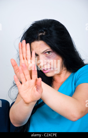 Abused scared woman with bruises on face sitting and showing stopping hands Stock Photo