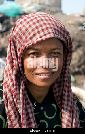 An Asian woman living in poverty is working at a polluted and toxic garbage dump in Cambodia. Stock Photo