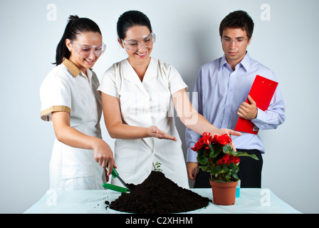 Three biologists working in laboratory ,they smiling and one of women showing to a plant in patchwork Stock Photo