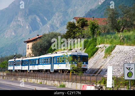 A commuter rural train passes by Lake Iseo in Marone region Lombardy Italy Stock Photo