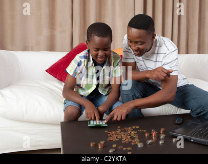 Man helping son count money using calculator, Johannesburg, South Africa Stock Photo