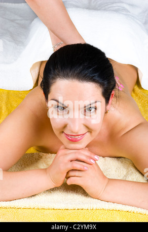 Smiling brunette woman enjoying a back massage at spa and sitting with hands under chin Stock Photo